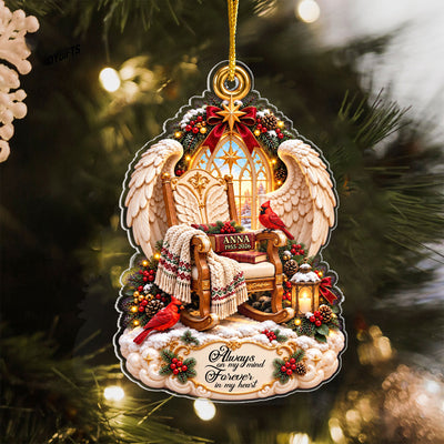 Personalized Angel Wings Memorial Acrylic Ornament hanging on a lit pine tree, rocking chair with ANNA 1955-2026