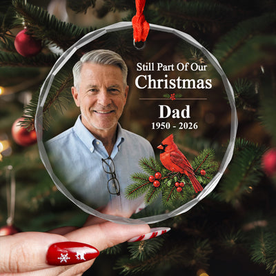 Personalized glass ornament custom photo held in a hand with red nails in front of a decorated Christmas tree