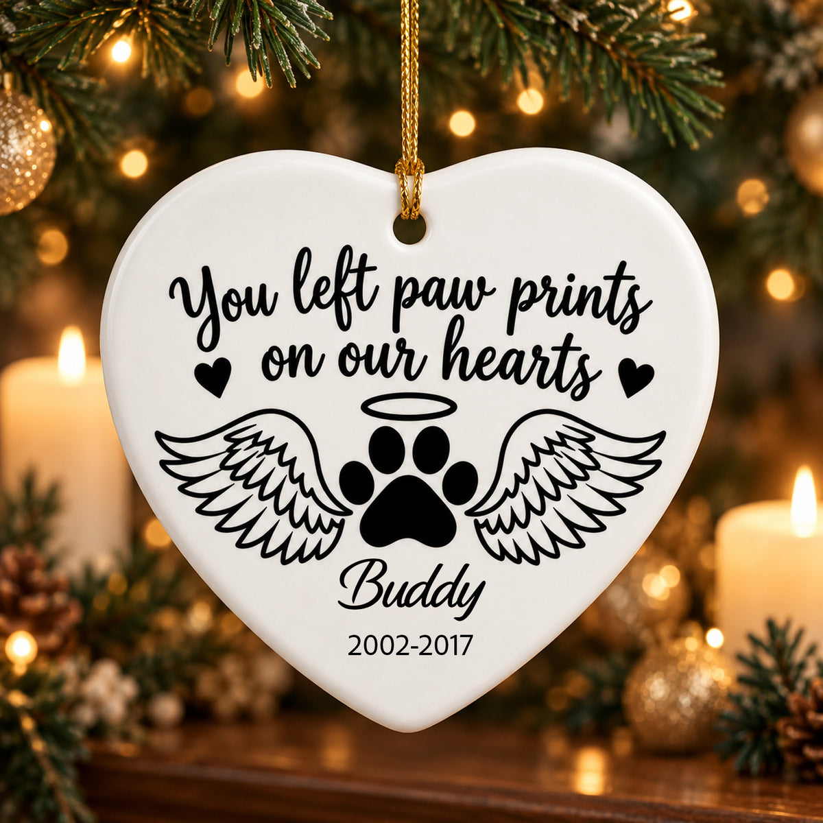 Personalized ceramic angel wings pet memorial ornament, heart shape with paw print and Buddy, hanging by tree and candles