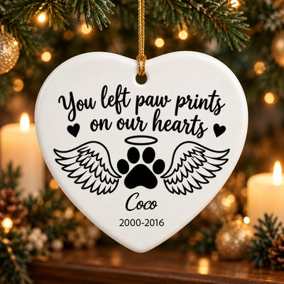 Personalized ceramic angel wings pet memorial ornament, heart shape with paw print and Coco, near candles and greenery