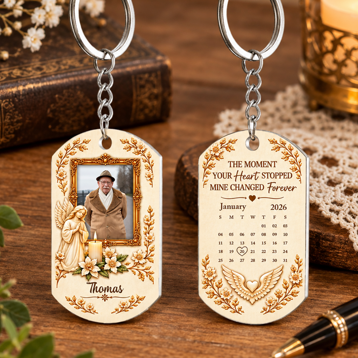 Personalized Stainless Steel Memorial Keychain front and back on a wooden table beside an old book and candle