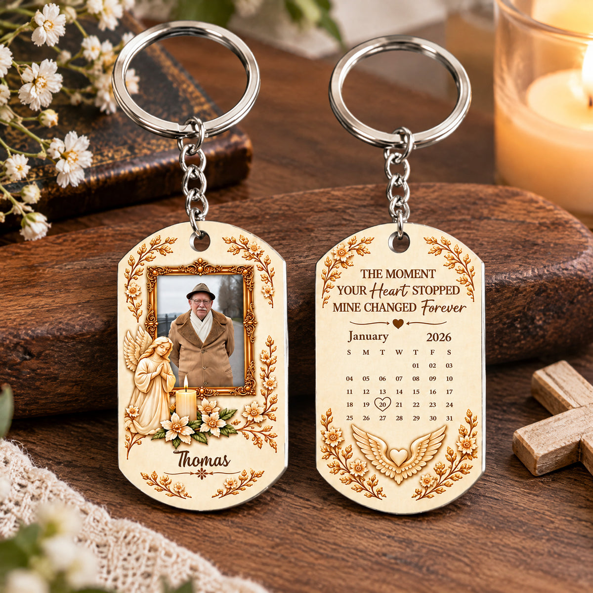 Personalized Stainless Steel Memorial Keychain front and back on a wood board with white flowers and a small wooden cross