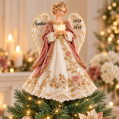 Personalized Angel Tree Topper with name and dates on wings, set on a lit tree beside candles and flowers