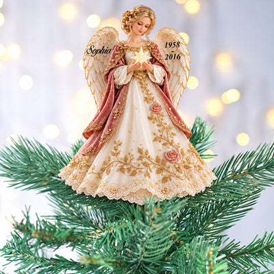 Personalized Angel Tree Topper in a close view on green branches with soft glowing lights behind